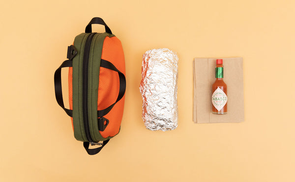 Texturized Orange Grab Bag next to a foil wrapped burrito and a bottle of Tabasco sauce.